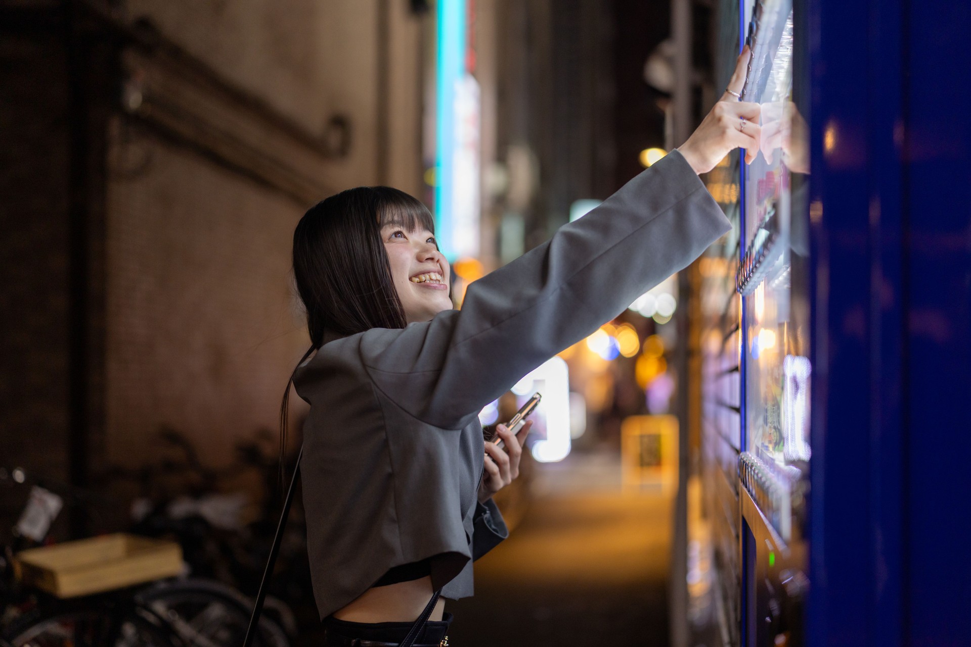 Young woman buying drink in vending machine after work